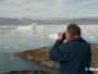 Un randonneur photographie le Fjord Sermilik encombré d'icebergs.