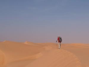 Une randonneuse marche sur des dunes dans le Sahara mauritanien