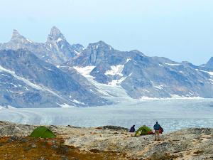 Un camp de randonneurs est installé face à un glacier en bordure de fjord au Groenland