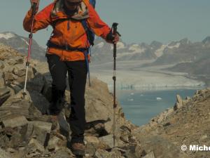 Une randonneuse descend un bloc rocheux non loin du Glacier Rasmussen au Groenland Est.