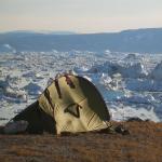 Tente de trek devant le fjord Sermilik chargé d'icebergs au Groenland Est