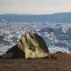 Tente de trek devant le fjord Sermilik chargé d'icebergs au Groenland Est