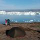 Deux randonneurs se tiennent dans un campement juste au bord du fjord Sermilik plein d'icebergs.