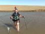 Randonneuse qui traverse un cours d'eau à pied en Mongolie.
